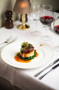a meal of steak on top of mashed potato and greens at marco pierre white's london steakhouse company