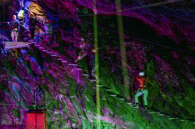 people climbing a ladder staircase underground in zip world caverns