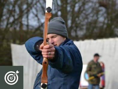 man holding a bow and arrow aiming towards the camera as part of an archery experience