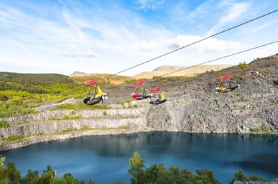 people on the zip lines going over the quarry lake at zip world velocity in wales