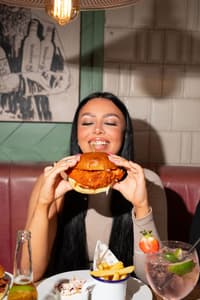 a women smiling while holding her burger