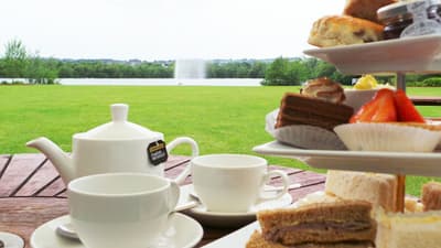 afternoon tea set up on a table outside in the gardens of the crown plaza hotel