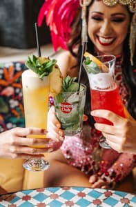 three ladies dressed in rio carnival dress enjoying cocktails on a tapas and cocktails experience at revolucion de cuba