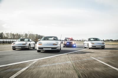 three sports cars and one police car side by side on a race track