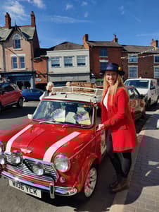 a woman standing next to a classic red mini cooper