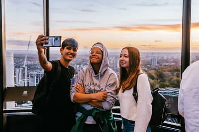 3 visitors taking a selfie at the top of lift 109 overlooking london at the battersea power station