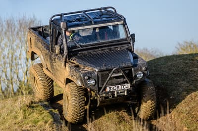 a mad max inspired land rover driving off road down a hill on a driving experience day