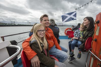 people sitting on the deck of a cruise boat on a daytime sightseeing cruise in scotland