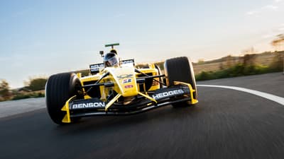 a front view of a yellow and black formula one race car on a race track as part of a driving experience