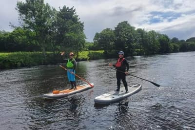 2 people paddle boarding on a river on an all day stand up paddle boarding experience day