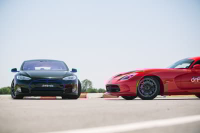 two supercars, a tesla and a viper, side by side on a race track.