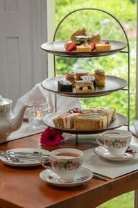 an afternoon tea set up on a cake stand with cups of tea on a table in front of a window at a hotel in ironbridge in shropshire