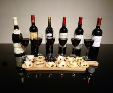bottles of red wine with a platter of cheese and crackers on a wine tasting experience with wine cottage