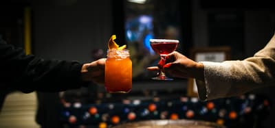 a shot of two arms each holding a different cocktail