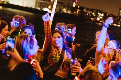 happy party goers on a silent sounds party river cruise on the thames in london