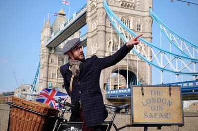 man with vintage bicycle in front of tower bridge on a london gin bike tour