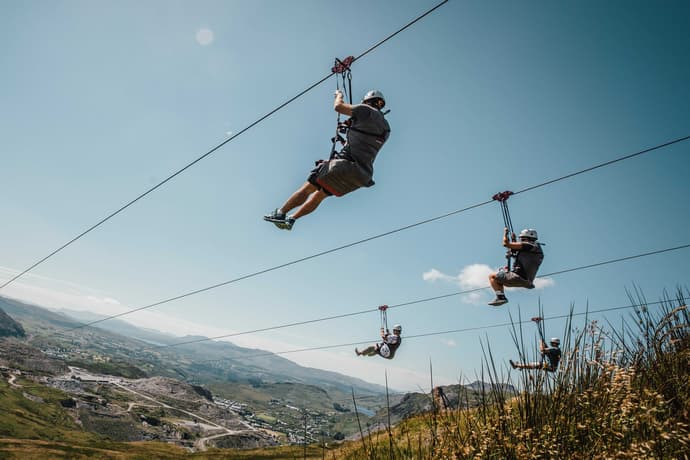 people on zip lines high over a quarry on the phoenix zip line experience at zip world