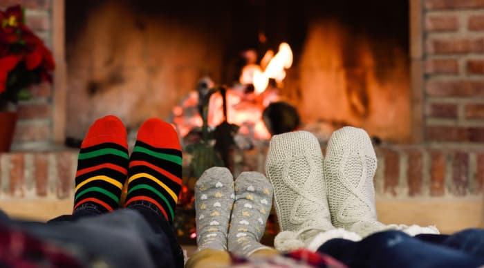 Feet in christmas socks with christmas tree in background covered in lights