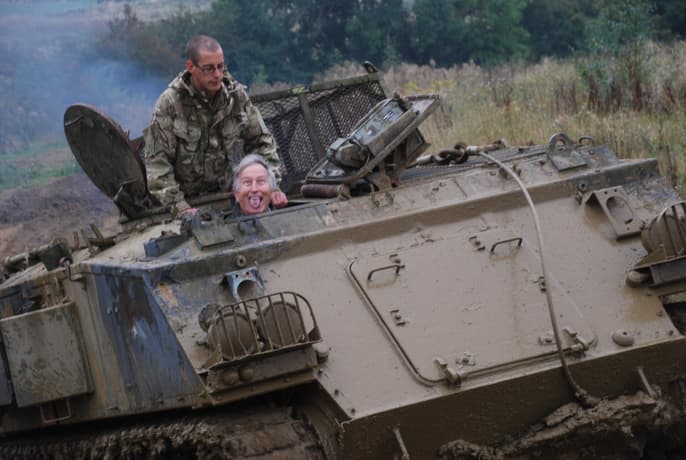 man pulling a silly face whilst driving a military tank on a tank driving experience day