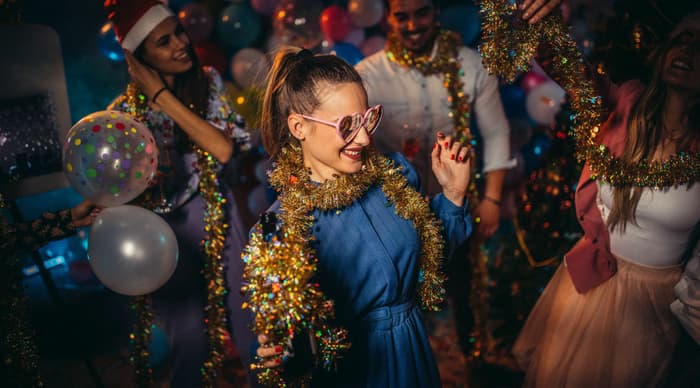 People dancing at a christmas party with tinsel wrapped around them