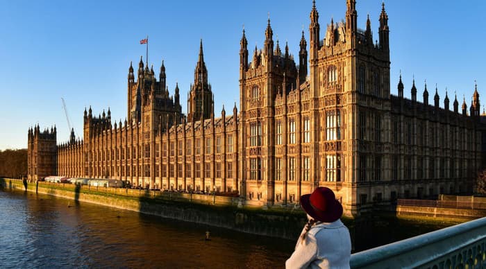 woman looking at houses of parliament from bridge in london on a short break
