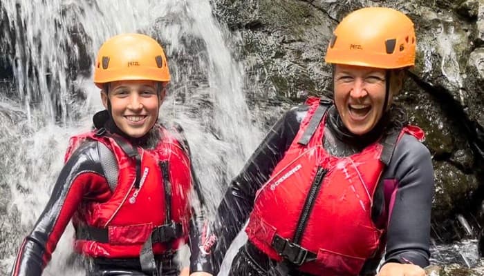 Young boy and woman standing in a waterfall
