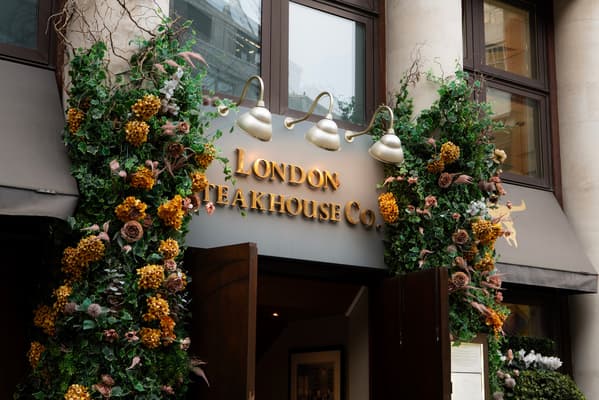 the front of marco pierre white's london steakhouse company with flowers around the doorway