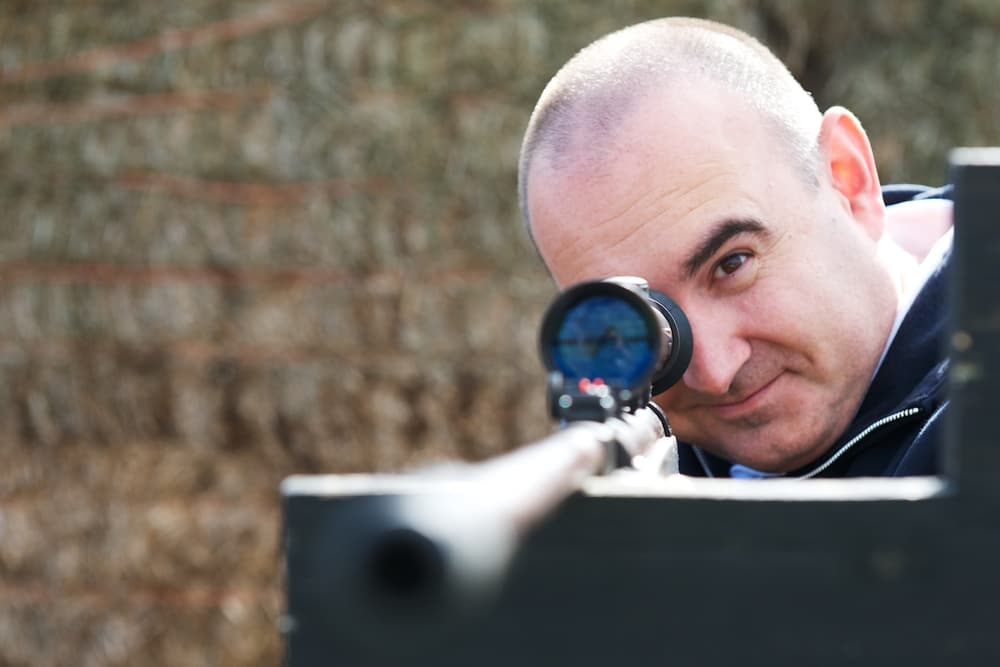 man aiming an air rifle while on a spy camp experience day for adults