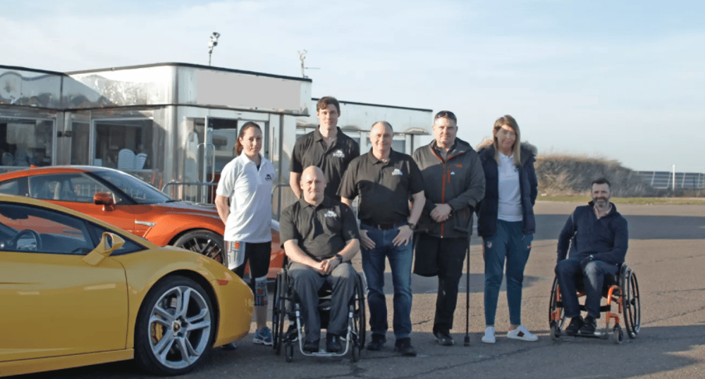 group of people standing next to sports cars to show accessible driving experiences