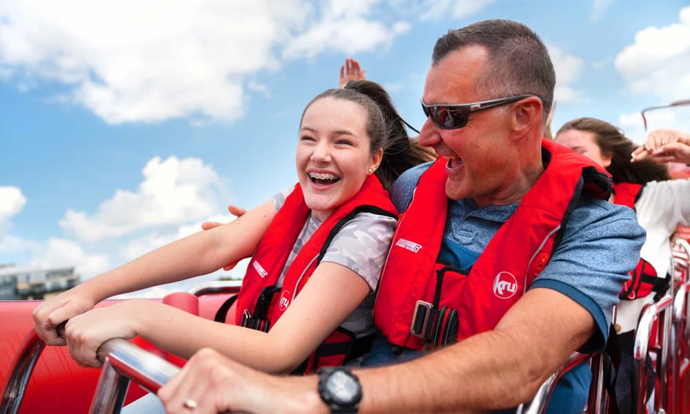 mans and young girl smiling while on a thames rockets explorer speedboat trip down the  thames in london