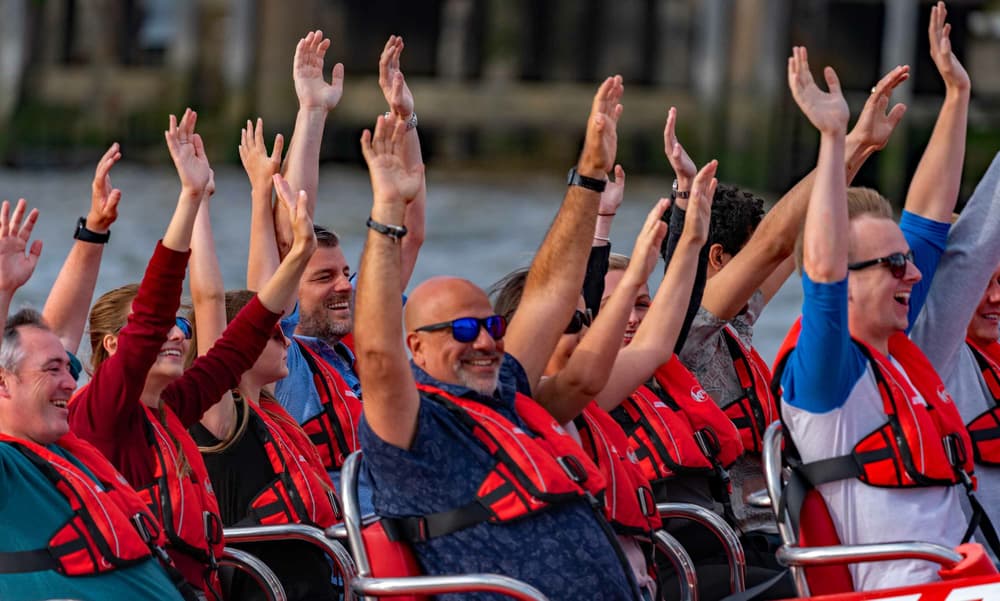 happy passengers with their arms in the air on a thames rockets ultimate speedboat experience on the thames in london