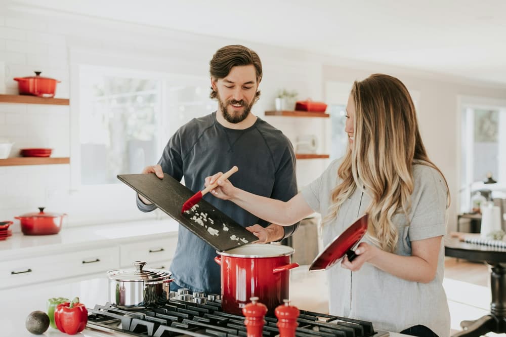 man and woman cooking together over a stove in a kitchen