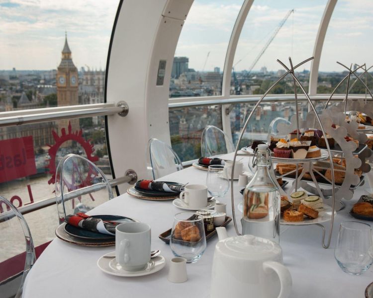 Afternoon tea laid out on a table with view of big ben on london eye
