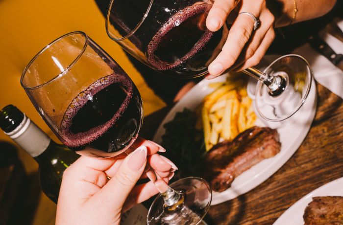 two people enjoying a steak dinner with bottle of house wine at revolution bars