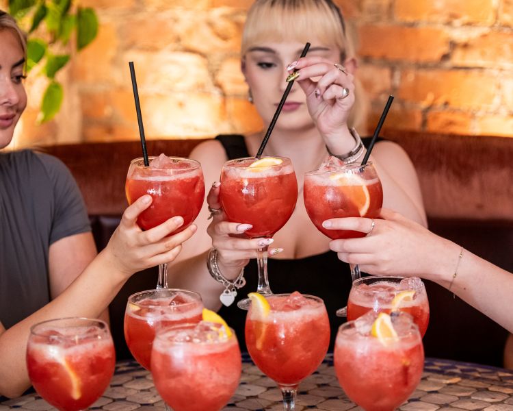 three ladies with a strawberry daiquiri cocktail tree at revolucion de cuba