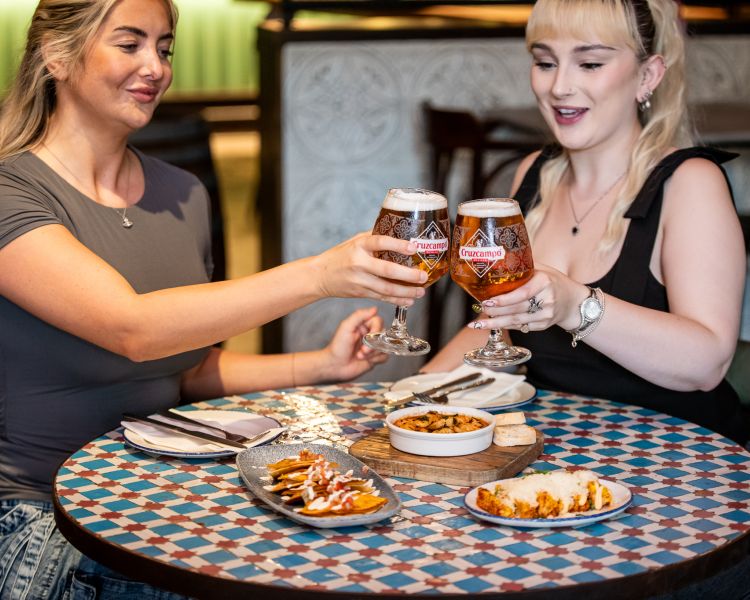 two ladies with beers and tapas dishes at revolucion de cuba