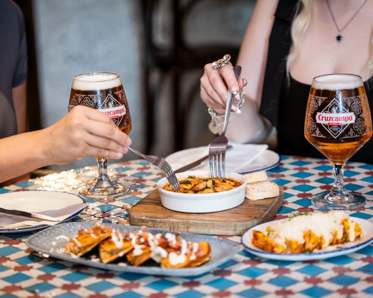 two ladies with beers and tapas dishes at revolucion de cuba