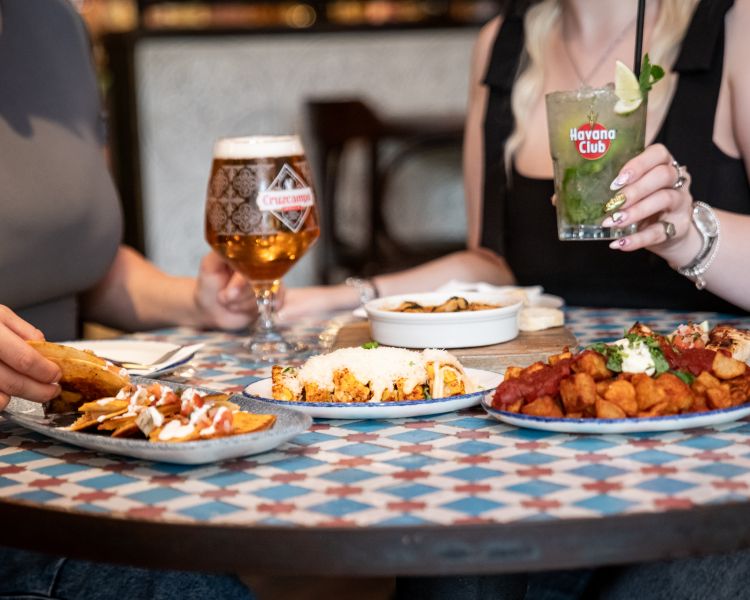 two ladies with bottomless drinks and tapas dishes at revolucion de cuba