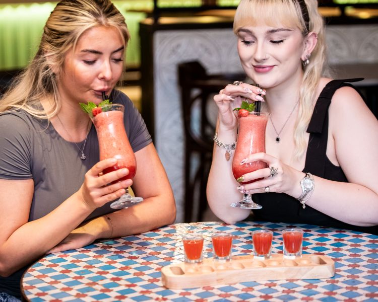 two ladies with strawberry daiquiris and margarita shots at revolución de cuba