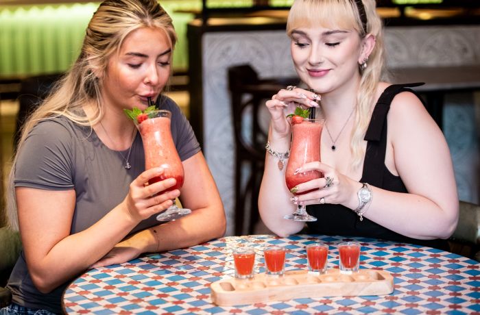two ladies with strawberry daiquiris and margarita shots at revolución de cuba