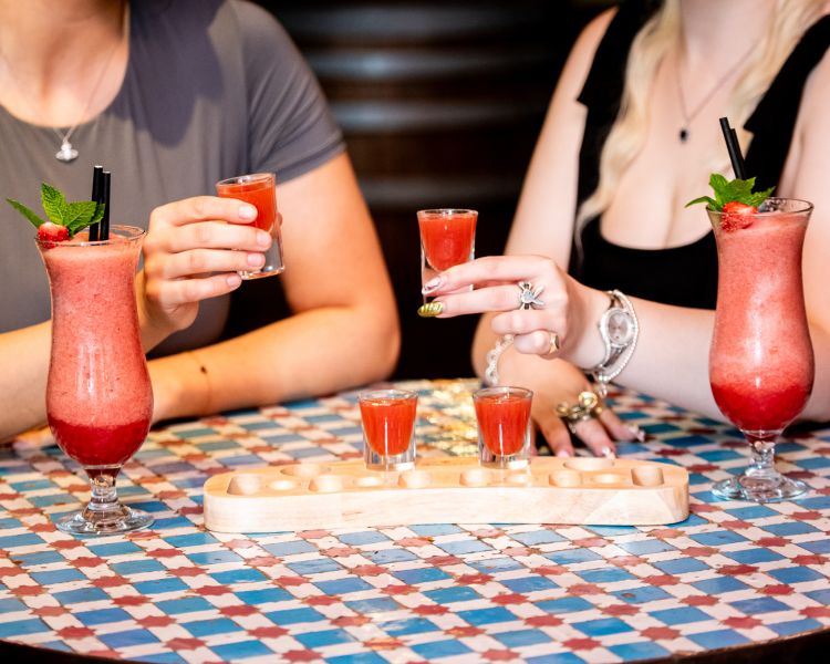 two ladies with strawberry daiquiris and margarita shots at revolución de cuba