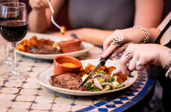 two ladies enjoying a steak meal and bottle of house wine at revolución de cuba