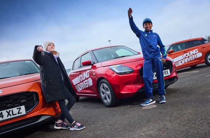 Two young drivers holding keys in front of cars