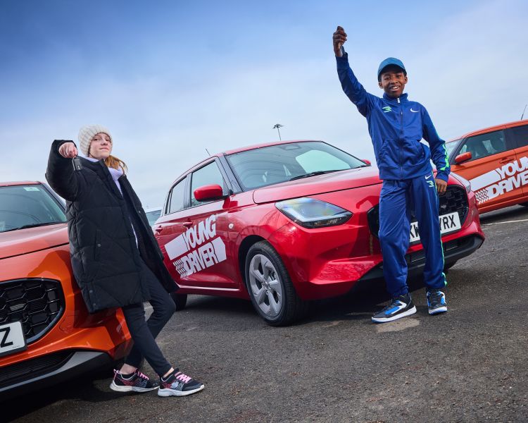 Two young drivers holding keys in front of cars