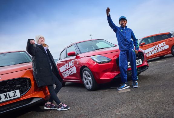 Two young drivers holding keys in front of cars
