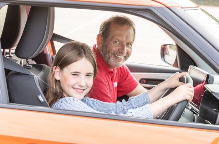 A young driver and instructor smiling in an orange car