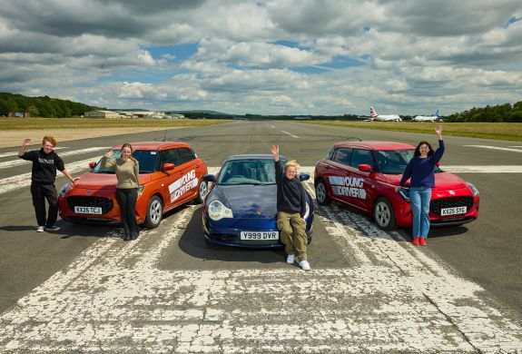 A group of young drivers in front of 3 cars