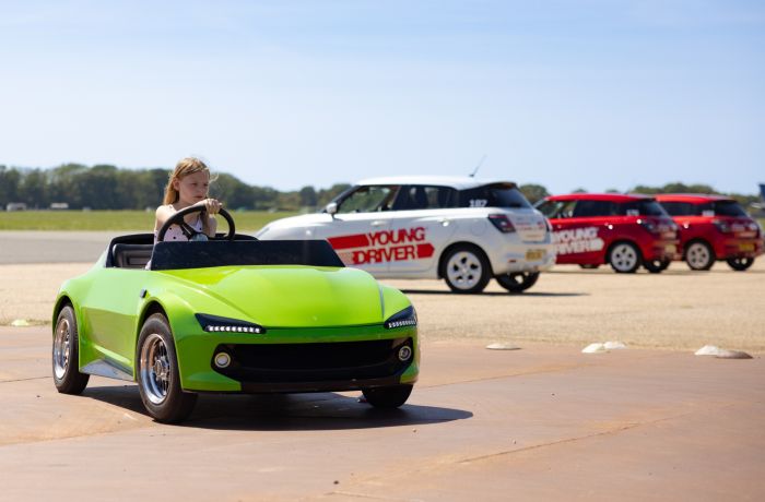 A young girl driving a green firefly car