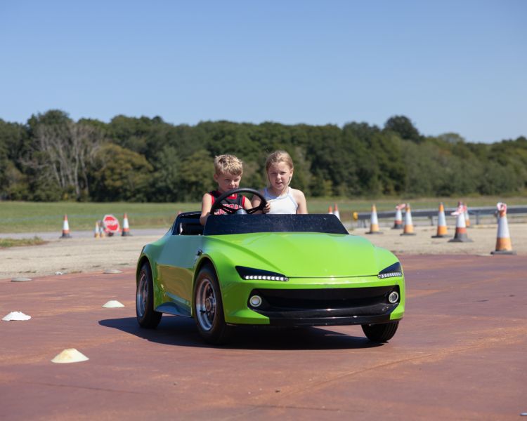Two young drivers in a green firefly car