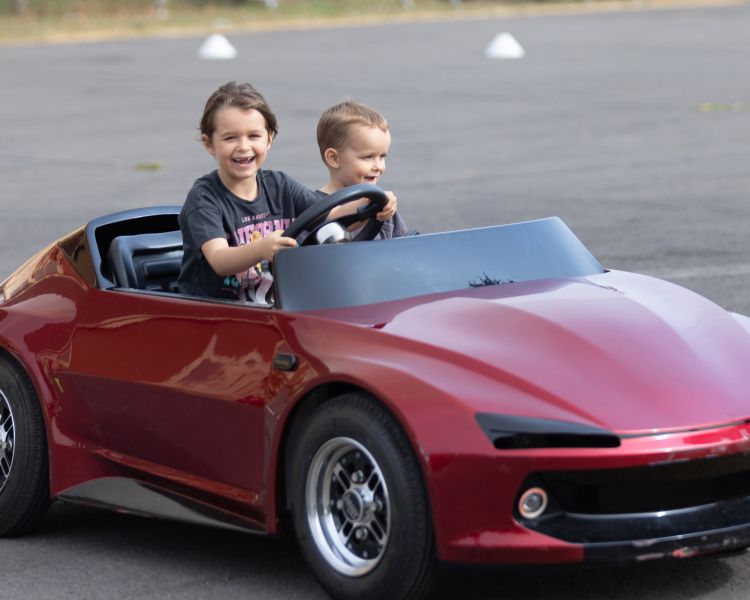 Two young drivers in a red firefly car